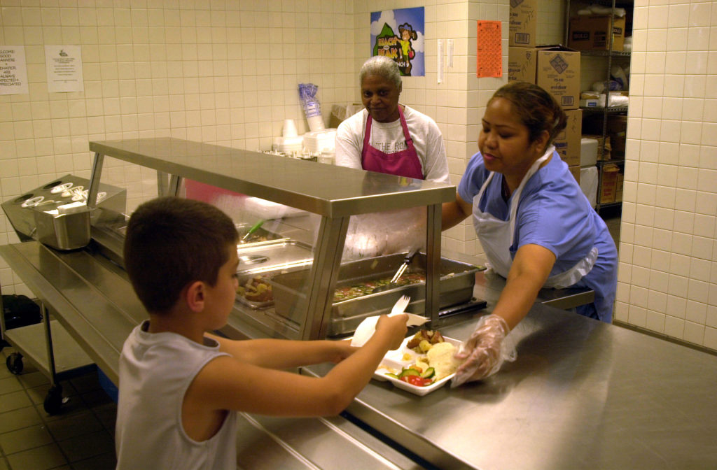Cafeteria employee handling lunch to student