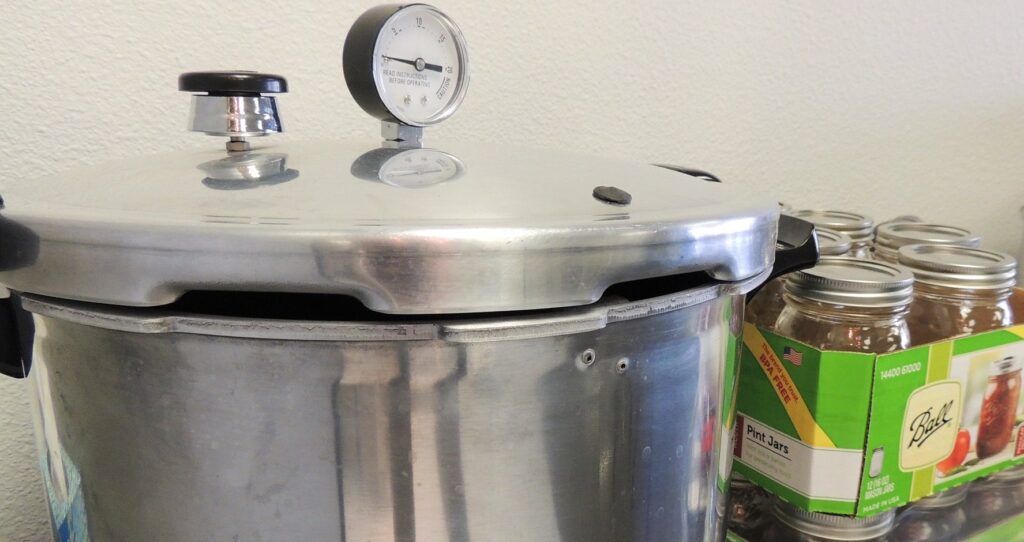 pressure canner and glass jars on a table.