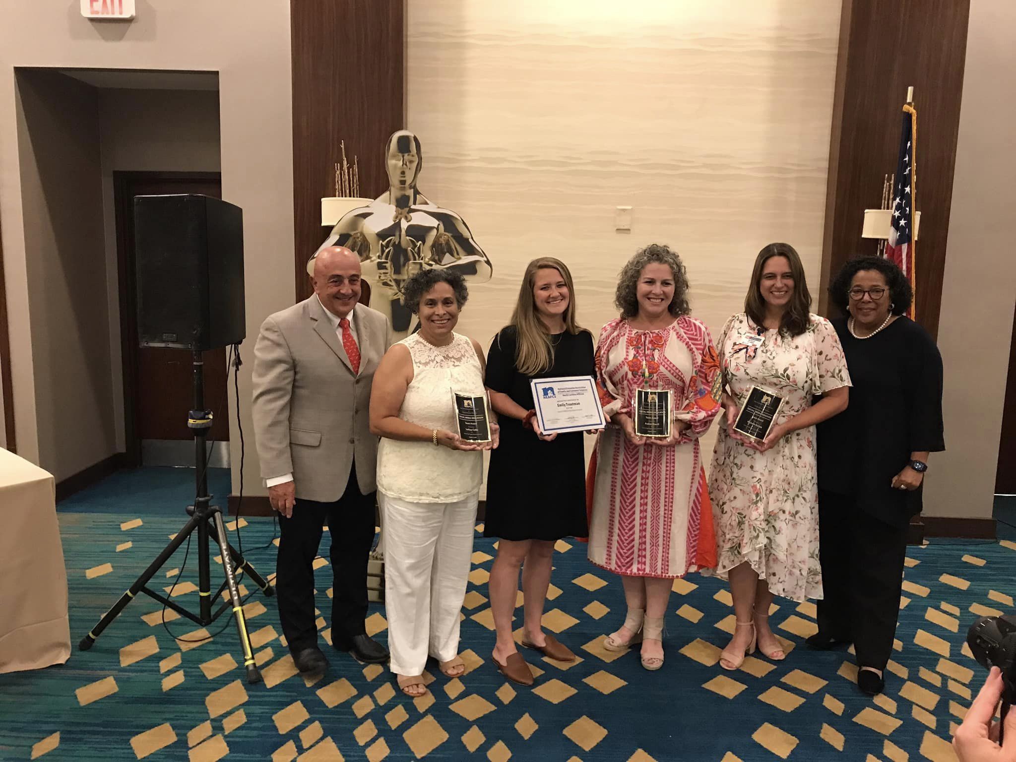 A group of people posing with awards and a certificate. 