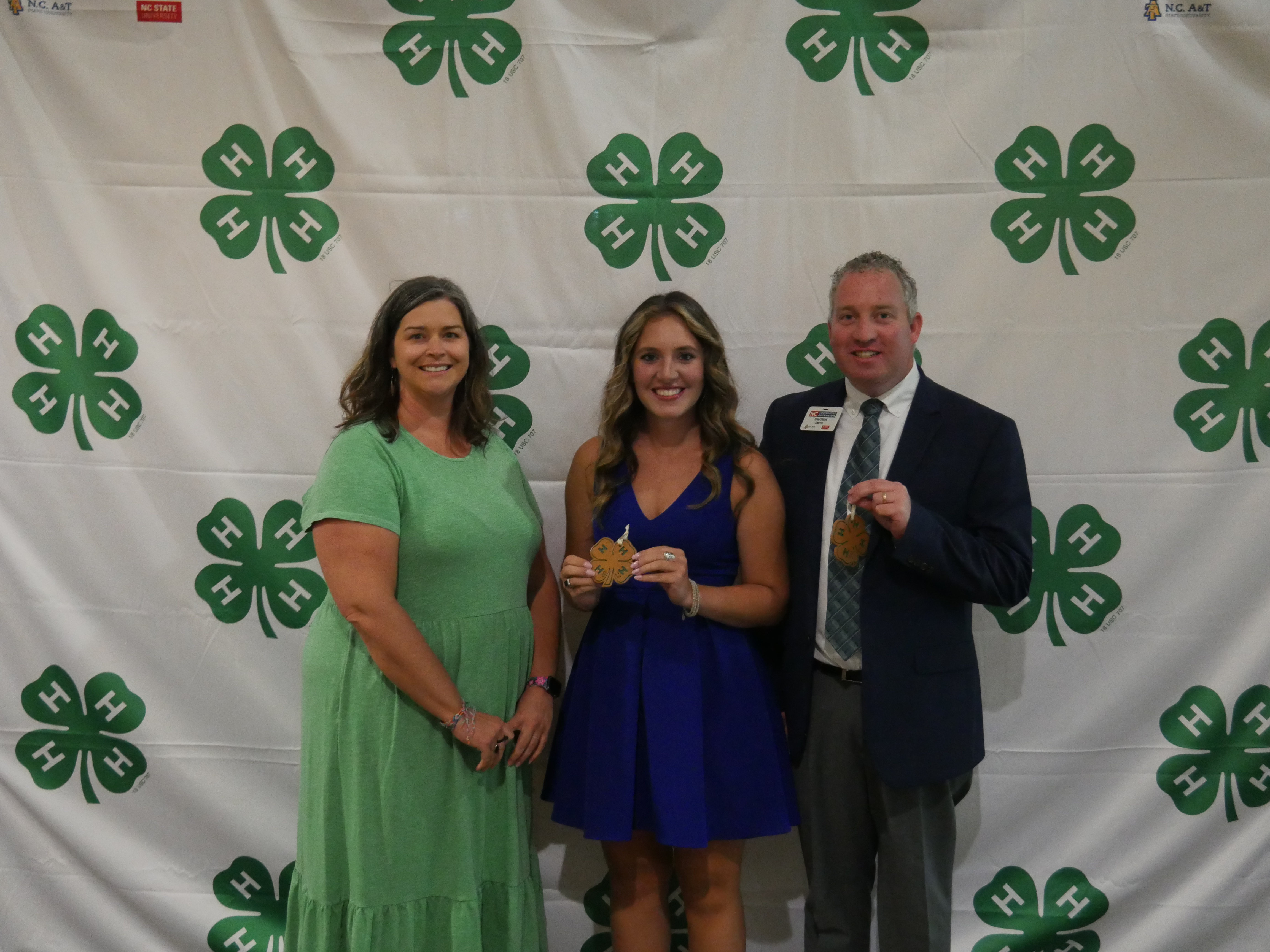 Three people pose with 4-H Clovers.
