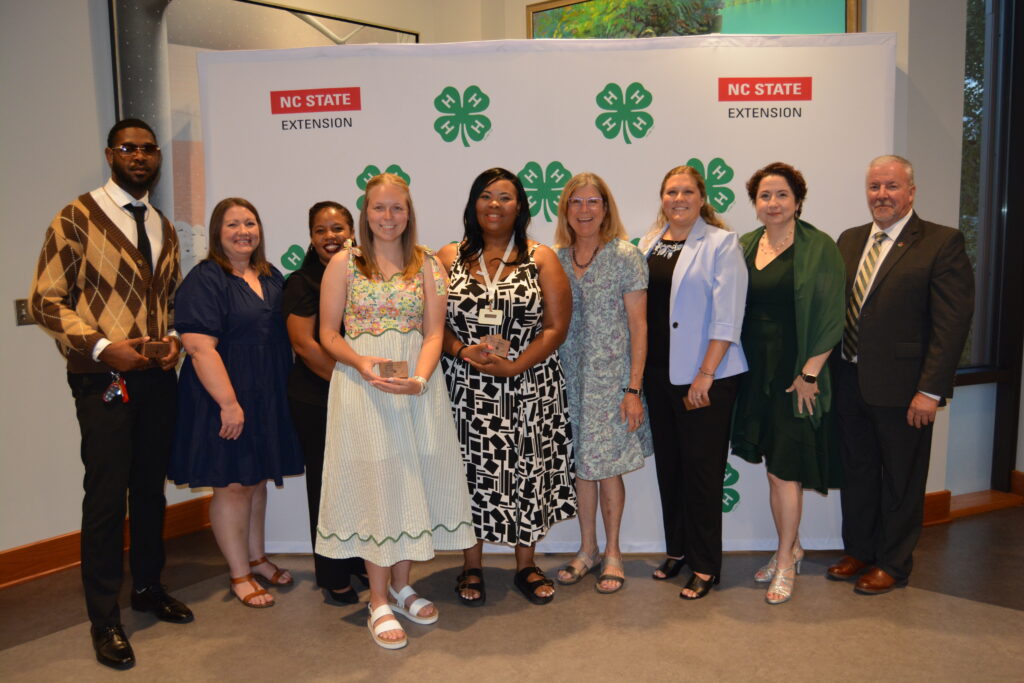 A group of people stand in front of a 4-H Banner.